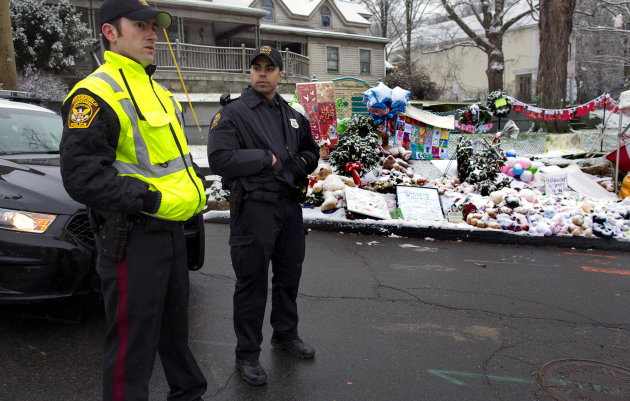 From left, Town of Ridgefield, Conn., Det. Durling, and Town of Greenwich, Conn., Officer Rivera stand near a memorial in Newtown, Conn. Tuesday, Dec. 25, 2012. Regional police agencies arrived in Newtown to relieve the local police force for the Christmas holiday. (AP Photo/Craig Ruttle)