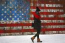 A woman walks by a U.S. flag mural on the side of a restaurant during a snow fall in the Williamsburg section of the Brooklyn borough in New York