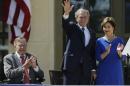 FILE - In this April 25, 2013, file photo, Former President George H.W. Bush, left, applauds with Laura Bush after former President George W. Bush's speech during the dedication of the George W. Bush Presidential Center in Dallas. Former President George H.W. Bush is publicly criticizing for the first time key members of his son's administration. A biography of the nation's 41st president to be published in November, 2015, contains his sharply critical assessments of former Vice President Dick Cheney and Defense Secretary Donald Rumsfeld. (AP Photo/David J. Phillip, File)