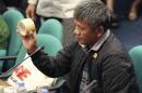 Former Filipino militiaman Edgar Matobato shows the kind of tape they use to wrap up dead bodies as he testifies before the Philippine Senate in Pasay, south of Manila, Philippines on Thursday Sept. 15, 2016. Matobato said that Philippine President Rodrigo Duterte, when he was still a city mayor, ordered him and other members of a squad to kill criminals and opponents in gangland-style assaults that left about 1,000 dead. (AP Photo/Aaron Favila)
