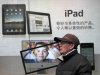 FILE - In this Jan. 26, 2011 file photo, a man stands near an advertisement for an Apple iPad  in Shanghai, China. News reports say more Chinese cities have seized iPads from retailers due to a dispute between Apple Inc. and a local company over ownership of the tablet computer's name. (AP Photo/Eugene Hoshiko, File)