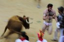 A reveler tries to escape a bull in the bull ring, at the end of third running of the bulls at the San Fermin fiestas, in Pamplona northern Spain, Monday, July 9, 2012. (AP Photo/Alvaro Barrientos)