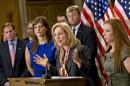 Sen. Kirsten Gillibrand, D-N.Y., is flanked by Sarah Plummer, left, a Marine Corps veteran and victim of sexual assault, and Kate Weber, right, a veteran who was sexually assaulted during her service in the Army, during a news conference on Capitol Hill in Washington, Tuesday, Nov. 19, 2013. They are surrounded by supporters of her proposal to let military prosecutors rather than commanders make decisions on whether to prosecute sexual assaults in the armed forces. At far left is Sen. Richard Blumenthal, D-Conn. Sen. Dean Heller, R-Nev., stands behind Sen. Gillibrand at center. (AP Photo/J. Scott Applewhite)