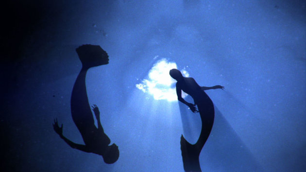 Mermaids swimming through the deep ocean.
