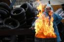A pro-Russia protester warms himself by the fire on a barricade outside a regional government building in Donetsk