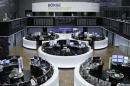 Traders work at their desks in front of the German share price index DAX board in Frankfurt