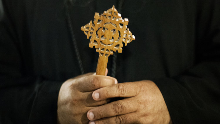 A Coptic Christian monk holds a Coptic cross at Al-Mahraq monastery during the preparation of a religious festival in Assiut, Upper Egypt, Tuesday, Aug. 6, 2013. Islamists may be on the defensive in Cairo, but in Egypt's deep south they still have much sway and audacity: over the past week, they have stepped up a hate campaign against the area's Christians. Blaming the broader Coptic community for the July 3, 2013 coup that removed Islamist President Mohammed Morsi, Islamists have marked Christian homes, stores and churches with crosses and threatening graffiti. (AP Photo/Manu Brabo)
