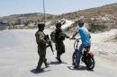 Israeli soldiers stop a Palestinian on his bicycle at the entrance of Yatta near the West Bank city of Hebron