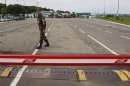 A Ukrainian border guard waits vehicles at a checkpoint in Shegyni, at the Ukrainian-Polish border