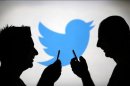 Men are silhouetted against a video screen with a Twitter logo as he poses with a Samsung S4 smartphone in this photo illustration taken in the central Bosnian town of Zenica