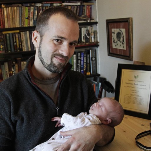 Author William Alexander poses with his 2-week old daughter, Iris, in his Minneapolis home on Friday, Nov. 16, 2012. Alexander won the Young People's Literature Prize at the National Book Awards in New York on Wednesday for his debut novel, "Goblin Secrets," a fantasy tale about a boy who joins a theatrical troupe of goblins to find his missing brother. (AP Photo/Jim Mone)
