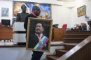 Pierre Denis, who works at Venezuela's embassy, carries an image of Venezuela's President Hugo Chavez after holding a Mass to pray for Chavez's health in Petion-Ville, Haiti, Friday, Dec. 21, 2012. Chavez is recovering in Cuba from surgery, his fourth operation related to pelvic cancer since June 2011. (AP Photo/ Photo/Dieu Nalio Chery)