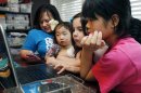 In this April 4, 2013 photograph, the Smith women, from left, mother Niki Smith, GiGi, 3, Macy Jade, 7 and Guan Ya, 14, use Google Translate on the family laptop to "speak" with their new daughter, Guan Ya, in their Rienzi, Miss., home. The Smiths and their children are using the Google Translate program to communicate almost exclusively with Guan Ya, who is deaf. The family uses iPhones, iPods and a laptop, all loaded with the program to write in either English that translates to Chinese or vice-a-versa. (AP Photo/Rogelio V. Solis)