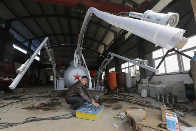 Zhang looks up as he squats under a suction pipe of his new submarine that captures sea cucumbers at his workshop in Wuhan, Hubei province