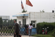 An unidentified U.S. Embassy employee, left, and Chinese official walk outside the closed gate at Specialty Medical Supplies plant where American Chip Starnes, co-owner of the plant, not in picture, is being held hostage at the Jinyurui Science and Technology Park in Qiao Zi township of Huairou District, on the outskirts of Beijing, China Monday, June 24, 2013. An American executive said Monday Starnes has been held hostage for four days at his medical supply plant in Beijing by dozens of workers demanding severance packages like those given to co-workers in a phased-out department. (AP Photo/Andy Wong)