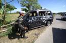 A soldier stands next to a damaged vehicle after a gunfight with Muslim rebels along a highway in Datu Saudi Ampatuan town, in the southern island of Mindanao on February 17, 2016