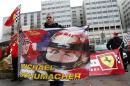 Philippe, a fan from Lyon, waves a flag as he attends a silent 45th birthday tribute to seven-times former Formula One world champion Michael Schumacher in front of the CHU hospital emergency unit in Grenoble, French Alps, where Schumacher is hospitalized
