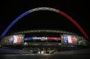The arch of London's Wembley Stadium is illuminated with the colours of the French national flag