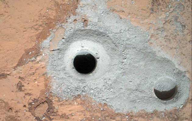 This image released by NASA on Saturday Feb. 9, 2013 shows a fresh drill hole, center, made by the Curiosity rover on Friday, Feb. 8, 2013 next to an earlier test hole. Curiosity has completed its first drill into a Martian rock, a huge milestone since landing in an ancient crater in August 2012. (AP Photo/NASA)
