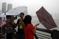 Tourists try to manage their umbrellas in rain and strong winds caused by Typhoon Muifa at the Bund, one of the most popular tourist destinations in town, in Shanghai, China, Sunday, Aug. 7, 2011. Typhoon Muifa is forecast to hit China early Monday morning, making landfall in the eastern province of Shandong and skimming the coast as it heads north, China's Central Meteorological Administration said. (AP Photo/Eugene Hoshiko)