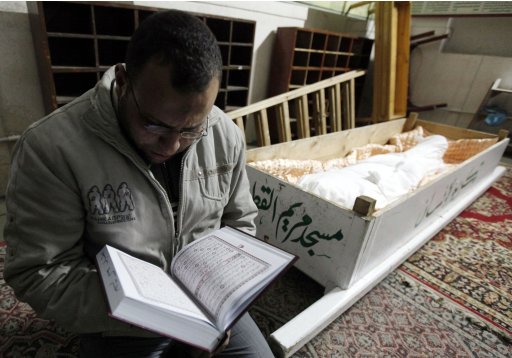 A brother of one of the soccer fans killed after clashes at an Egyptian soccer match reads the Koran next to his brother's body in Port Said city