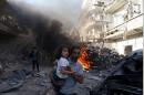 A man carries a girl reacting at a site hit by what activists said were airstrikes by forces loyal to Syria's President Bashar al-Assad on a market place in the Douma neighborhood of Damascus, Syria