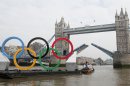 A tug boat pulls a barge with giant Olympic rings that are 11 meters (36 feet) tall and 25 meters (82 feet) wide towards Tower Bridge as they are unveiled on the River Thames in London, Tuesday, Feb. 28, 2012. A giant set of Olympic rings was launched on to the River Thames today to mark 150 days until the start of the London Games. (AP Photo/Alastair Grant)