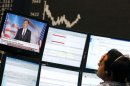 A share trader sits next to a TV showing news on U.S. Republican presidental candidate Romney in front of the German share price index DAX board at the German stock exchange in Frankfurt