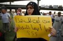 An Iraqi woman's placard reads "How can all the officials account for their funds?" during a demonstration against corruption and poor services on August 7, 2015 in Najaf