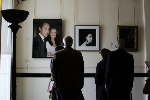 People look at a photograph of Prince William and his wife Kate the Duchess of Cambridge taken before they were married by Mario Testino in 2010 and a photograph of the late Princess Margaret, center,