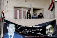 Syrians stand above a poster of Syrian President Bashar al-Assad (L) and Lebanese Hezbollah Leader Hassan Nasrallah hanging on the wall of a building in the western city of Homs. Assad vowed to defeat a "conspiracy" against Syria, as US Secretary of State Hillary Clinton branded a rare speech he delivered the day before as "chillingly cynical". (AFP Photo/Joseph Eid)