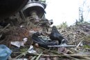 Shoes and clothing lie next to a cargo train known as "the Beast," after it derailed near the town of Huimanguillo, southern Mexico, Sunday, Aug. 25, 2013. The cargo train, carrying at least 250 Central American hitchhiking migrants derailed in a remote region, killing at least five people and injuring dozens, authorities said. (AP Photo/Christian Palma)