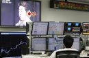 An employee of a foreign exchange trading company looks at monitors as a television set shows Japan's incoming Prime Minister and the leader of Liberal Democratic Party (LDP) Shinzo Abe speaking in Tokyo