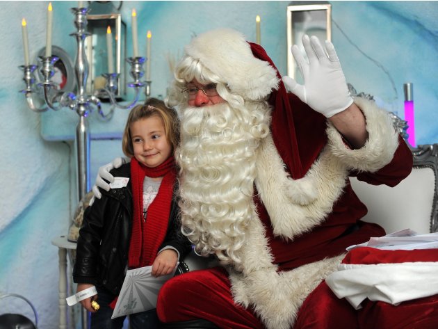 A young girl poses for photographs with Santa Claus during a tour of Santa's grotto at Selfridges department store in central London