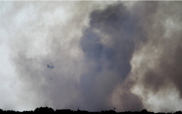 A helicopter moves in to drop water on a wildfire at Possum Kingdom Lake, Texas, Wednesday, Aug. 31, 2011, the day after it swept through the neighborhood and destroyed 25 homes. (AP Photo/LM Otero)