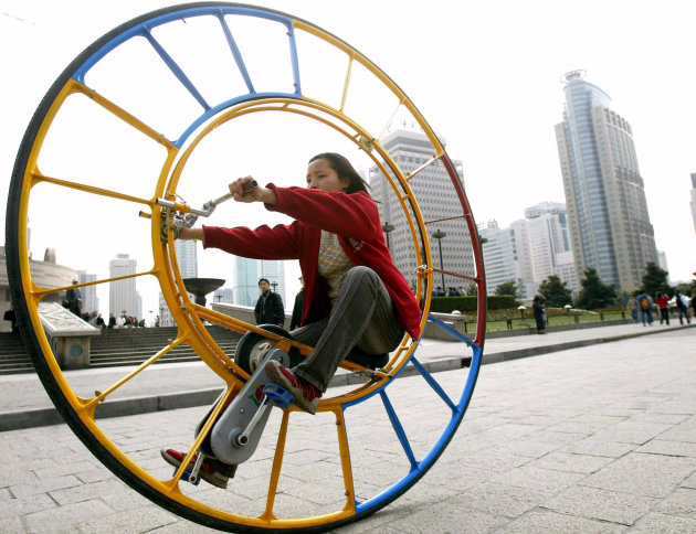 WOMAN RIDES AN UNICYCLE IN SHANGHAI.