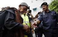 A police officer checks a man's identity in Kuala Lumpur, Malaysia, Saturday, July 9, 2011. Malaysian police said Friday, they would shut major roads and suspend public transportation into Kuala Lumpur's city center to thwart opposition-backed activists, who vowed Friday to press ahead with a banned rally for electoral reforms. (AP Photo/Lai Seng Sin)