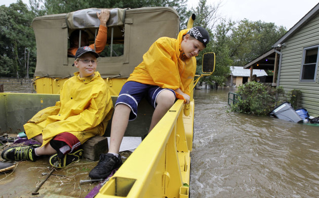 William Pillus, 13, right, and his brother Michael Pillus, 10, ride in the back of their neighbor Gary Leusink's truck as they ride into Leusink's property through floodwaters from Hurricane Irene, Su