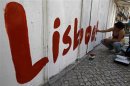 A political activist paints the word "Lisbon" on a wall at a street in Lisbon