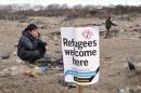 A migrant stands next to a banner on January 23, 2016 in the French port city of Calais, northern France, during a demonstration to support the migrants and refugees who live in the 'jungle'