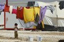 A Syrian refugee boy stand outside his family's tent at Al Zaatri refugee camp in Mafraq