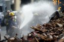 A firefighter sprays the debris in the aftermath of a building collapse, Thursday, June 6, 2013, in Philadelphia. On Wednesday, the building under demolition collapsed onto a neighboring thrift store, killing six people and injuring 14, including one who was pulled from the debris nearly 13 hours later. (AP Photo/Matt Rourke)