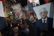 Palestinians celebrate as they wave posters of former Palestinian leader Yasser Arafat, left, and President Mahmoud Abbas, right, as they watch the U.N. General Assembly votes on a resolution to upgrade the status of the Palestinian Authority to a nonmember observer state, in the west bank city of Ramallah, Thursday, Nov. 29, 2012. The U.N. General Assembly has voted by a more than two-thirds majority to recognize the state of Palestine. The resolution upgrading the Palestinians' status to a nonmember observer state at the United Nations was approved by the 193-member world body late Thursday by a vote of 138-9 with 41 abstentions. (AP Photo/Majdi Mohammed)