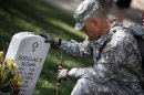 A member of the U.S. Army Old Guard pays his respects at the grave of U.S. Army Major Douglas Sloan, before placing a flag at one of the over 220,000 graves of fallen U.S. military service members buried at Arlington National Cemetery