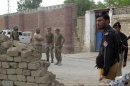Policemen and Ranger soldiers stand outside a prison following a Taliban attack in Dera Ismail Khan