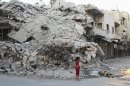 A girl stands in front of building damaged by what activists said was shelling by forces loyal to President al-Assad in Idlib