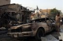 File picture shows a man looking at a damaged vehicle a day after a bomb attack in Baghdad