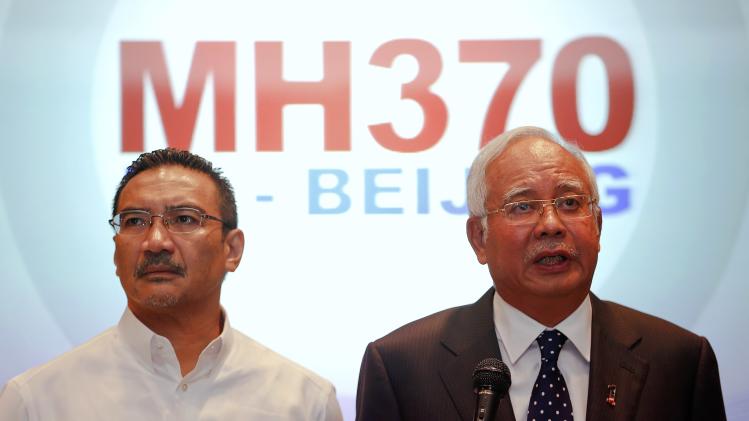 Malaysian PM Najib addresses reporters as Transport Minister Hussein stands by him, at Kuala Lumpur International Airport
