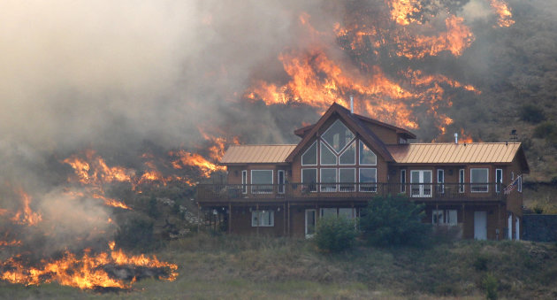 In this photo taken Tuesday, Aug. 14, 2012,  flames surround a house on a hillside above Bettas Road near Cle Elum, Wash. A spokesman for the Washington state Department of Natural Resources said the 