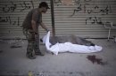 In this Thursday, Sept. 20, 2012 photo, a worker moves bodies near Dar Al Shifa hospital in Aleppo, Syria. Dozens of Syrian civilians were killed on Thursday, four children among them, in artillery shelling by government forces in the northern Syrian town of Aleppo. (AP Photo/Manu Brabo)